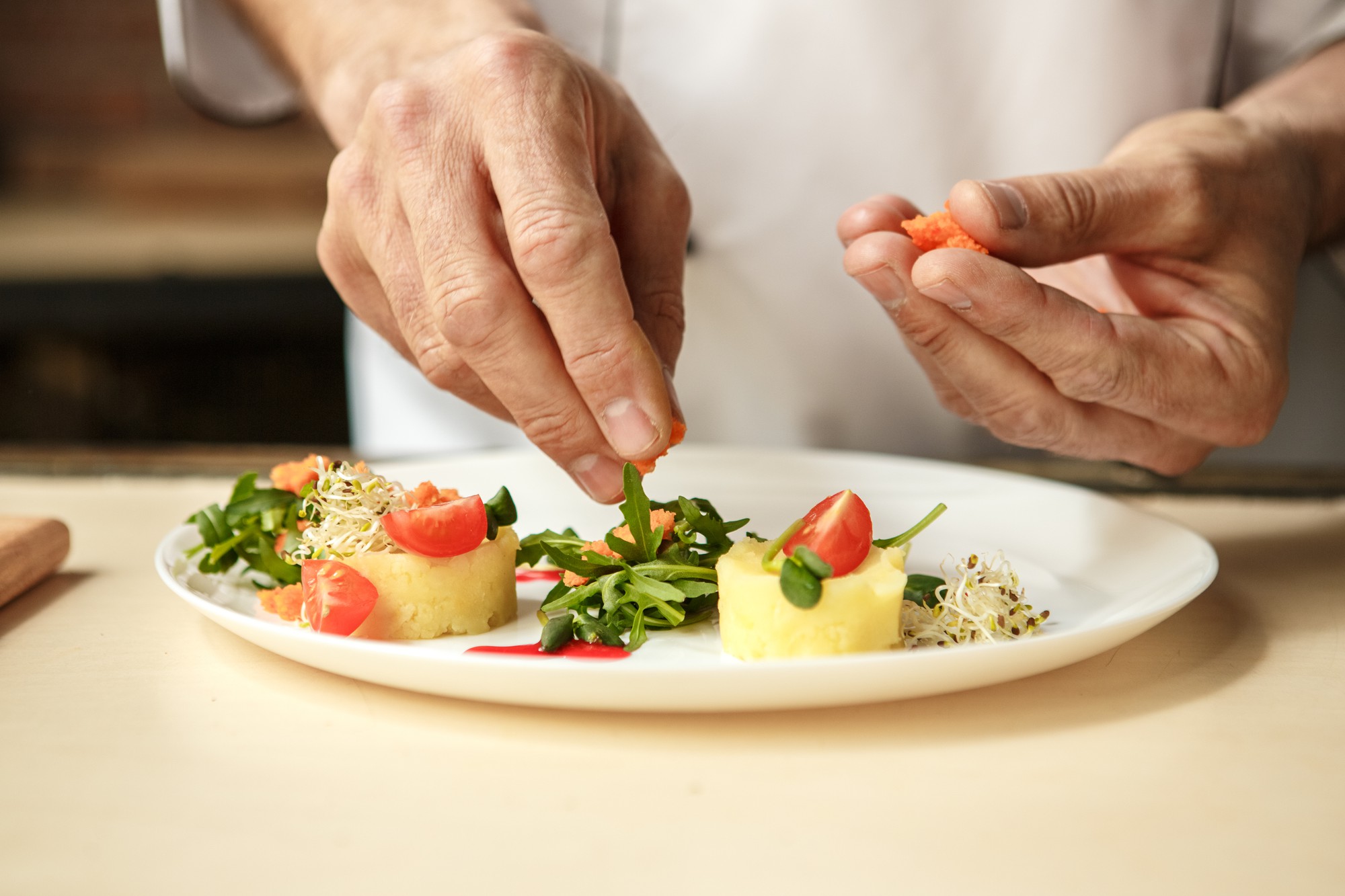 Instructor arranging plated seasonal dish on wooden counter